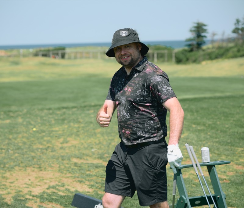 A player in a bucket hat giving a thumbs up on the range