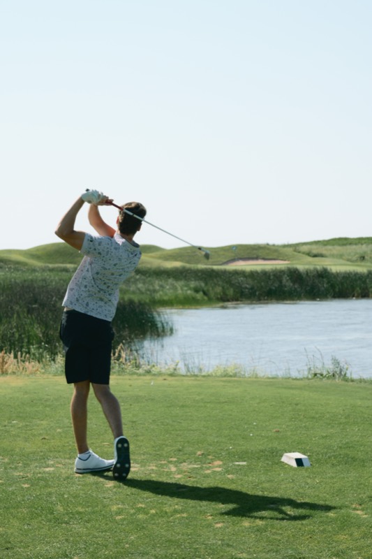 A player following a tee shot across water at Crowbush
