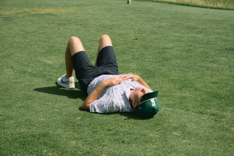 A player lying flat on his back on a green