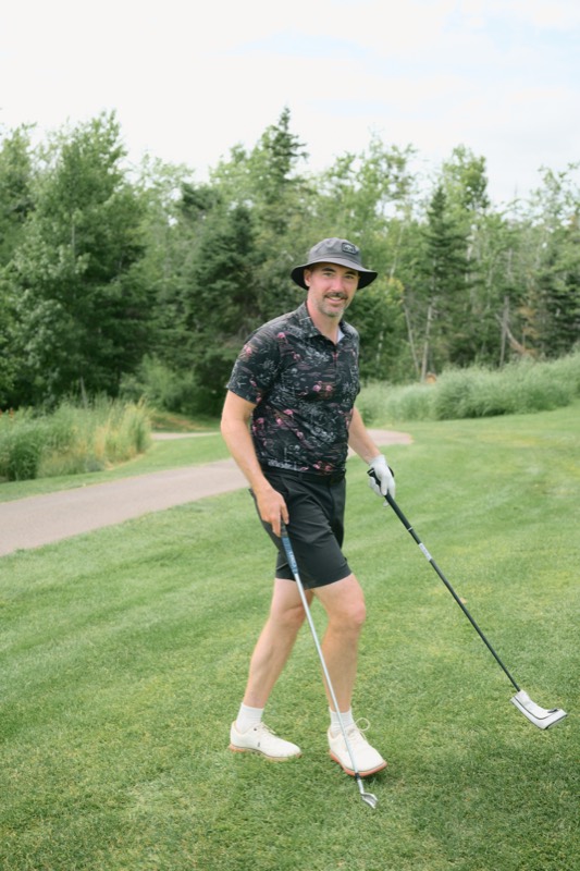 A player in a bucket hat walking off with a putter