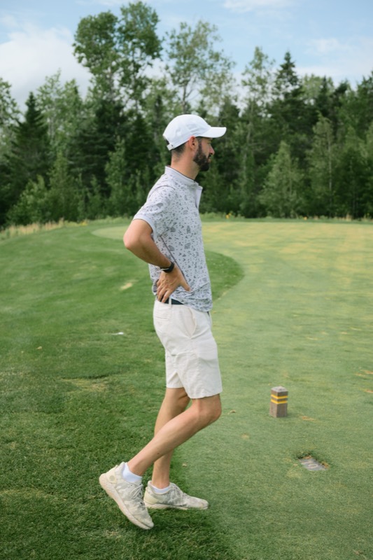 A player standing with hands on hips beside a tee marker