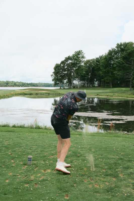 A Flamingos player striking a tee shot over water