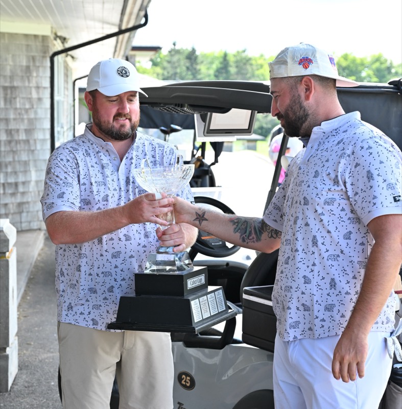 Two Bears players passing the cup between them beside a cart