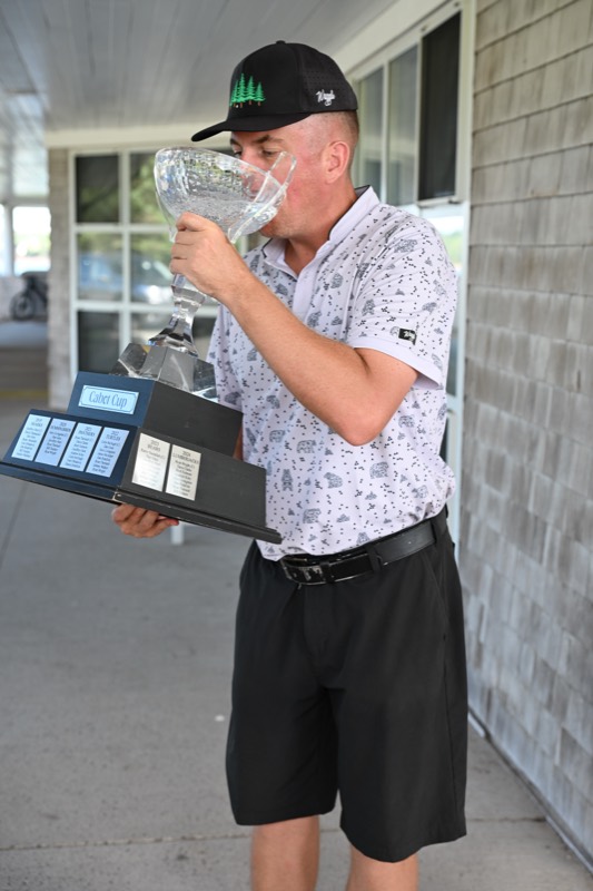 A player tipping the cup back under the clubhouse canopy