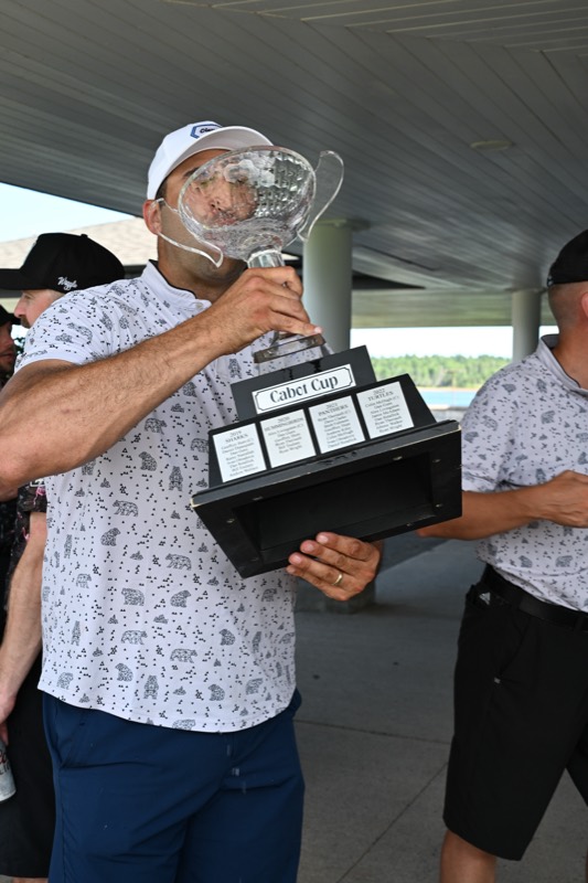 A player lifting the cup with both hands under the pavilion