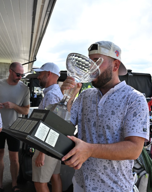 A bearded player drinking from the cup with teammates behind