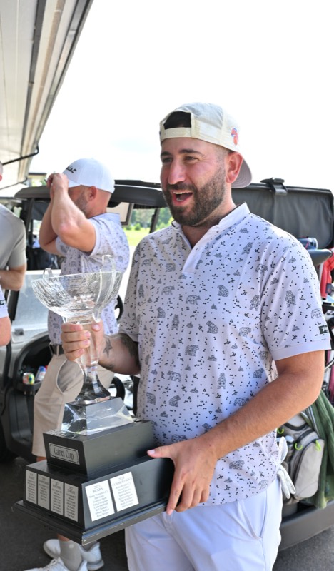 A grinning player carrying the cup past the carts