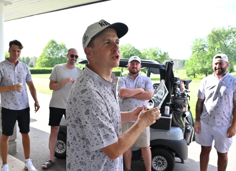 A player addressing the group holding cash and a golf ball